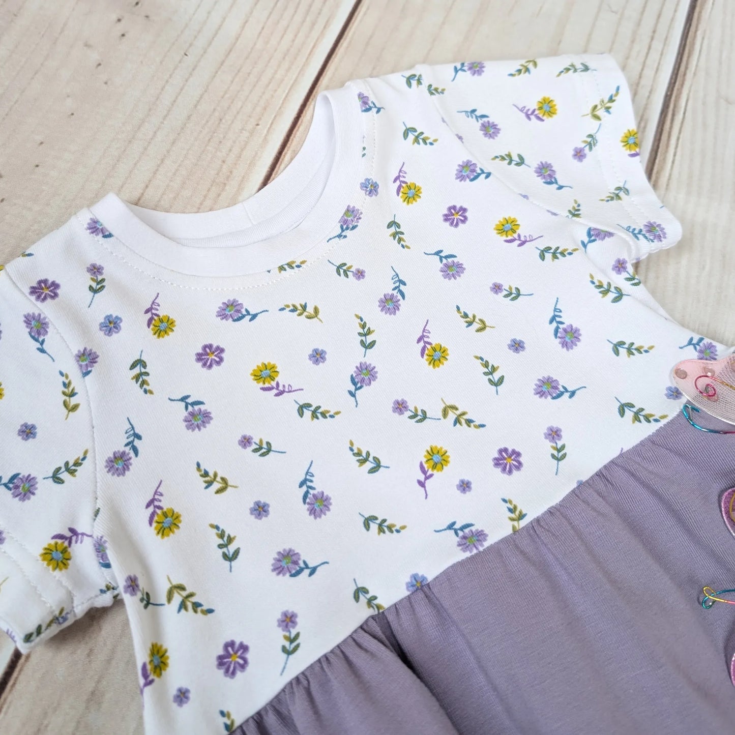 White bodice with a yellow & lilac floral pattern on a wooden surface