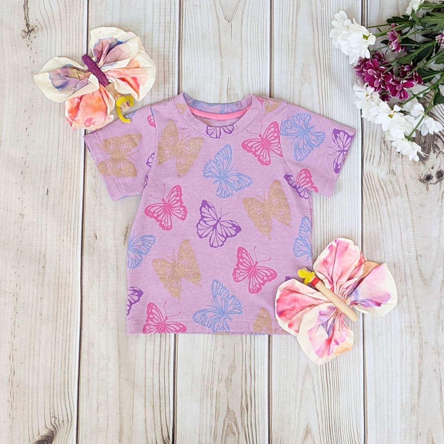 flatlay-glitter-gold-glitter-blue-pink-purple-butterflies-background-lilac-t-shirt
