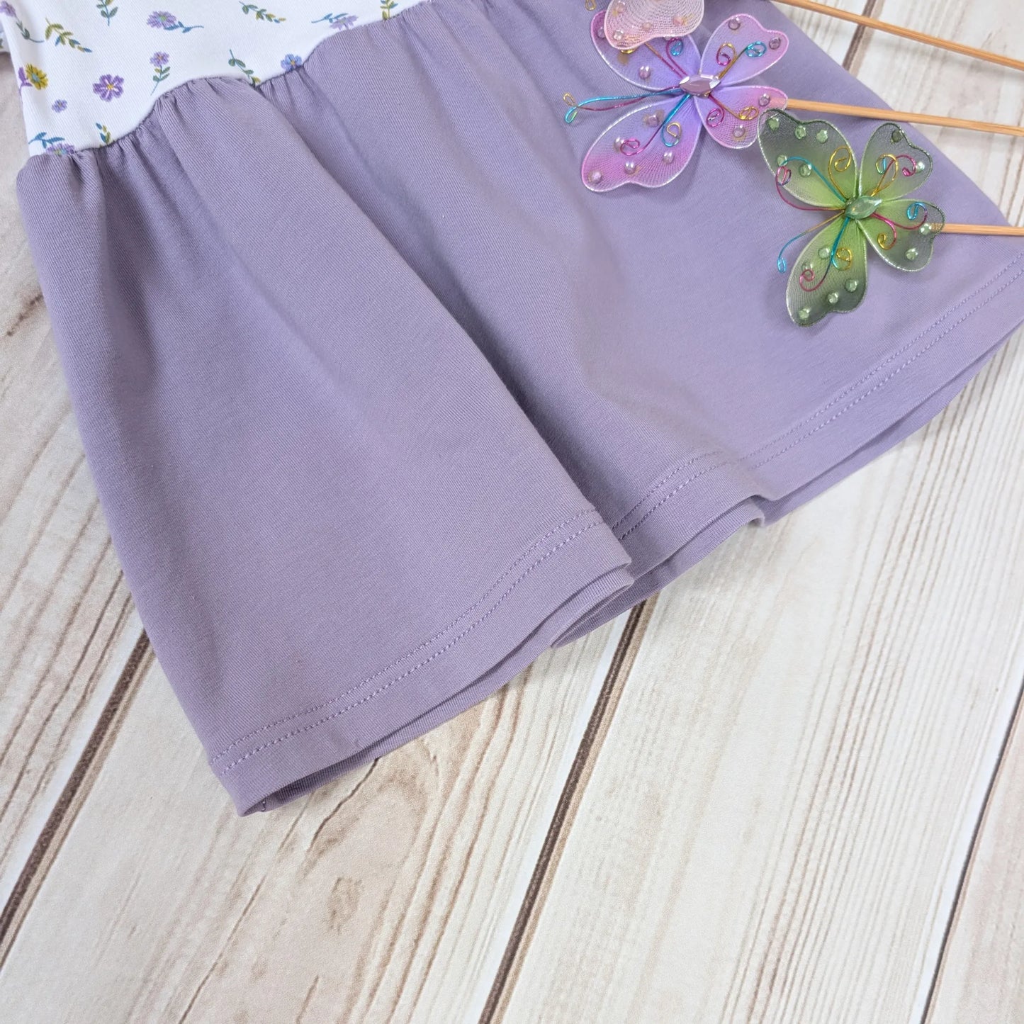 Purple skirt on gathered dress with butterfly decorations on a wooden surface