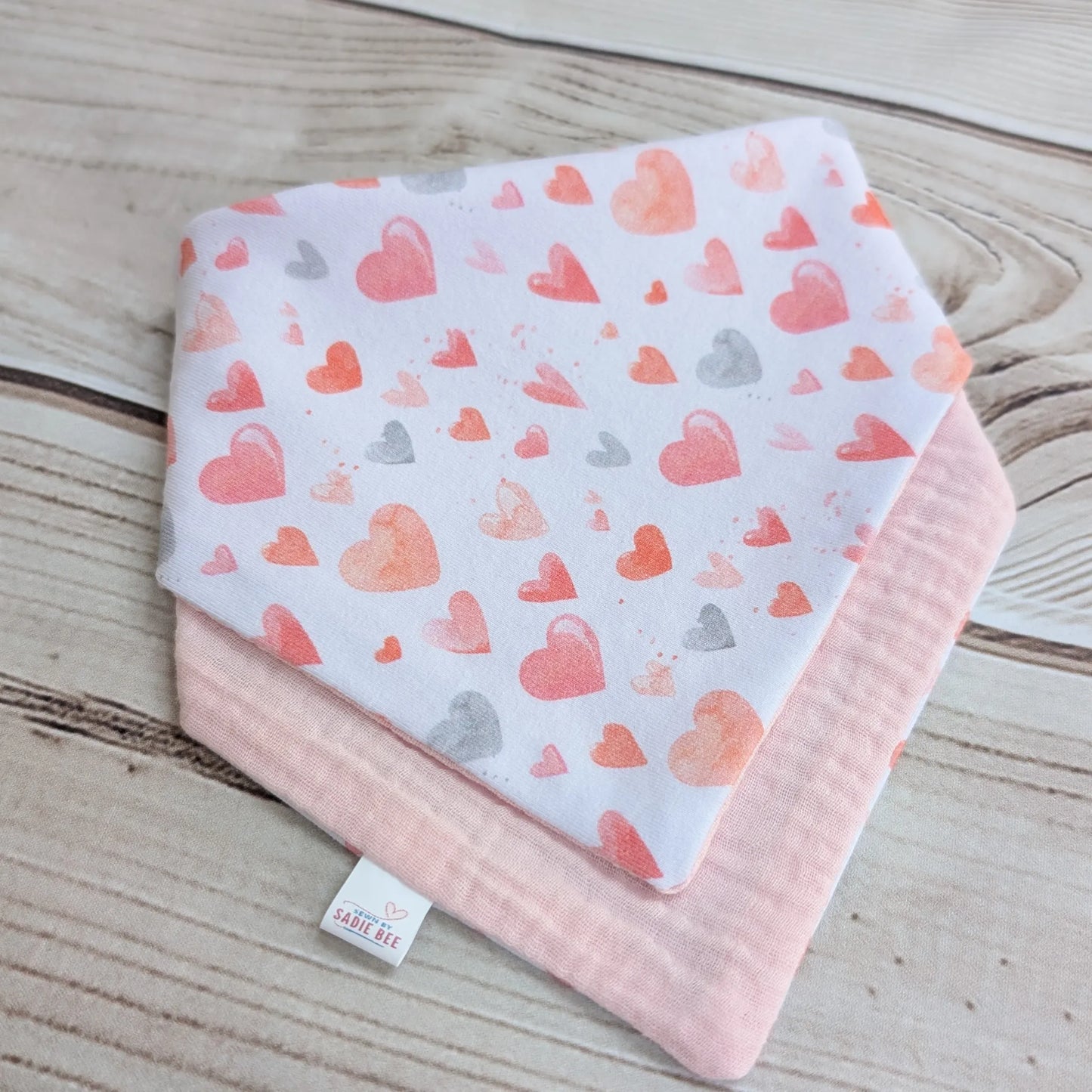 Baby bib folded with heart pattern on a wooden surface
