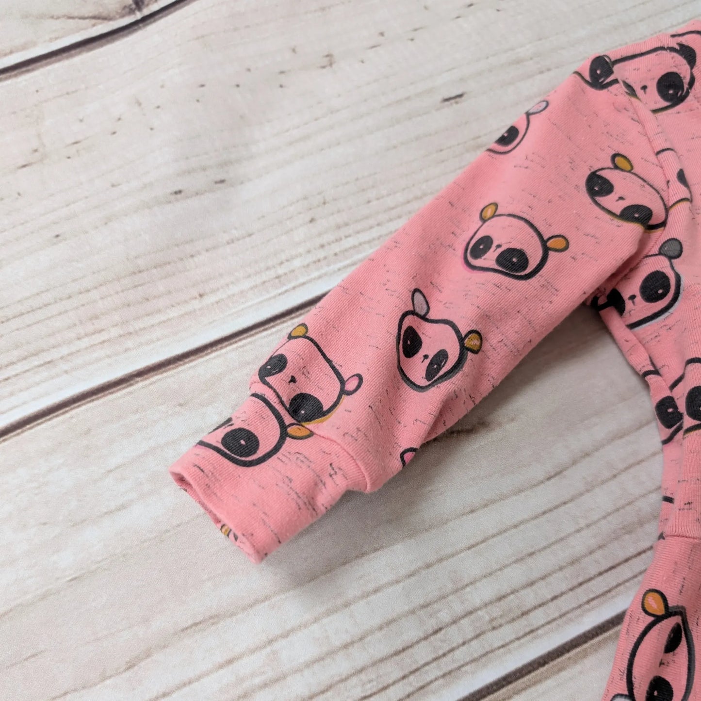 Pink Panda Dress showing Sleeve and Cuff on a wooden Surace