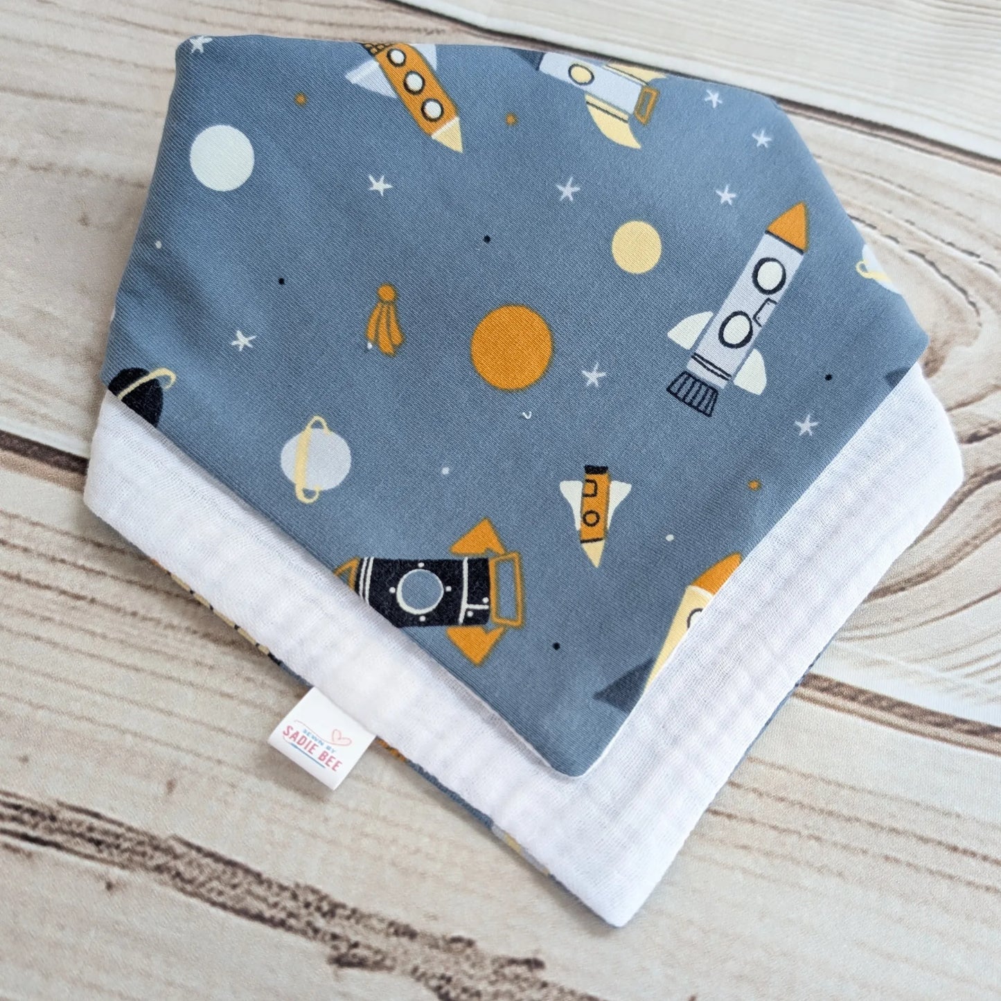 Baby bib with space-themed design on a wooden surface