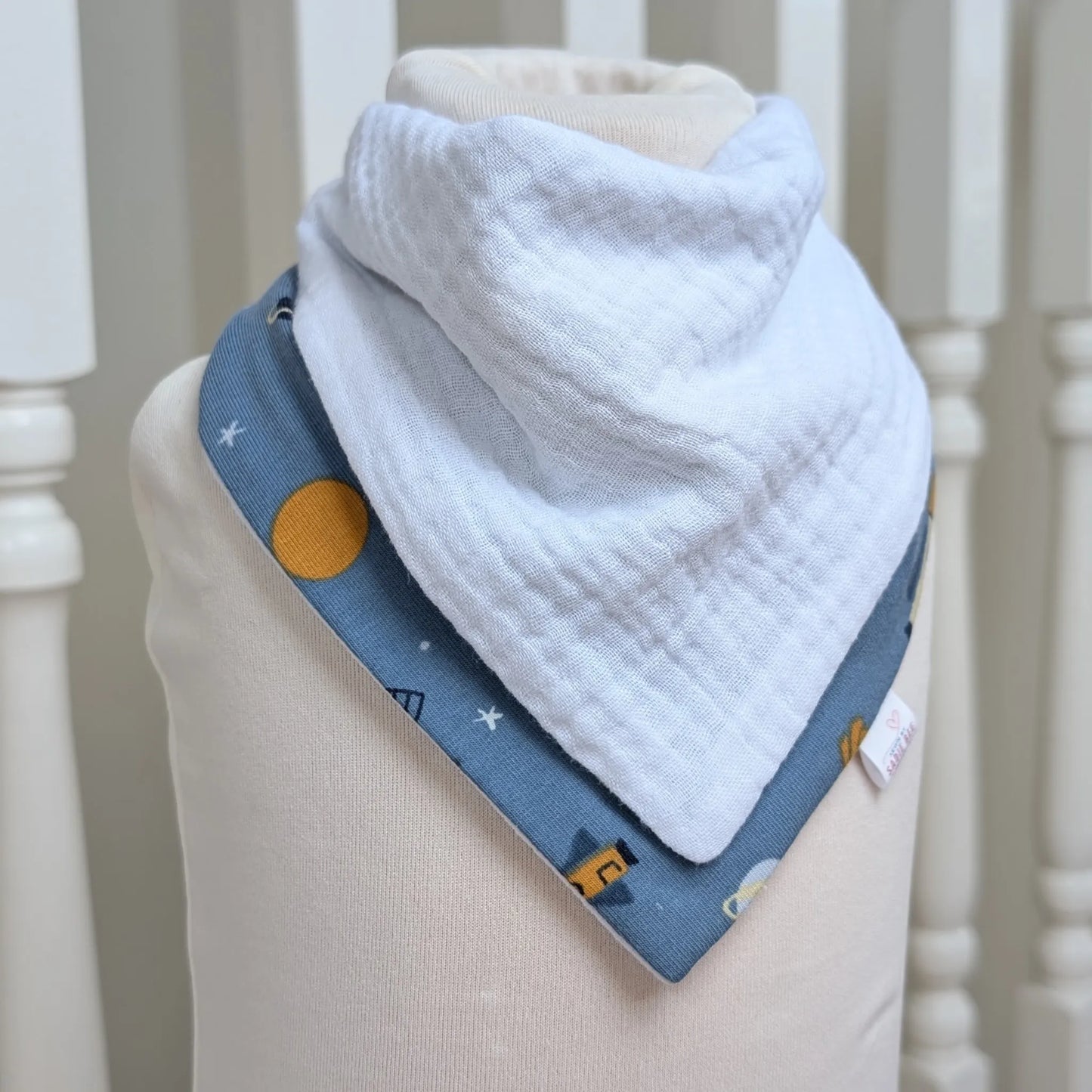 Baby bib with blue spacce rocket design on a mannequin against a neutral background