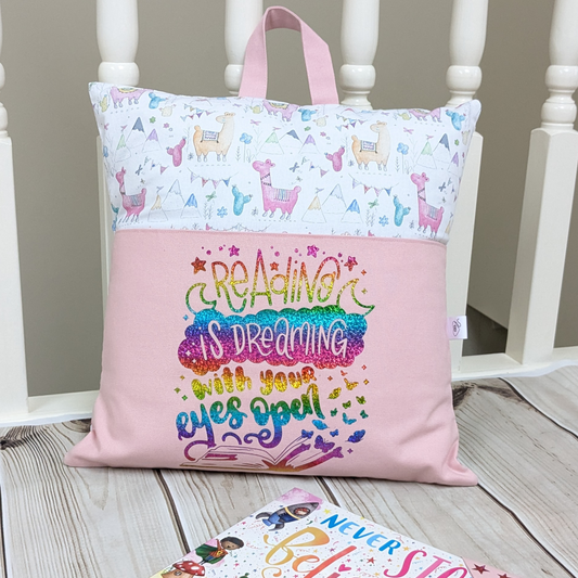 Alpaca designed pocket reading cushion to keep books in. Slogan says Reading is Dreaming with your Eyes Open.