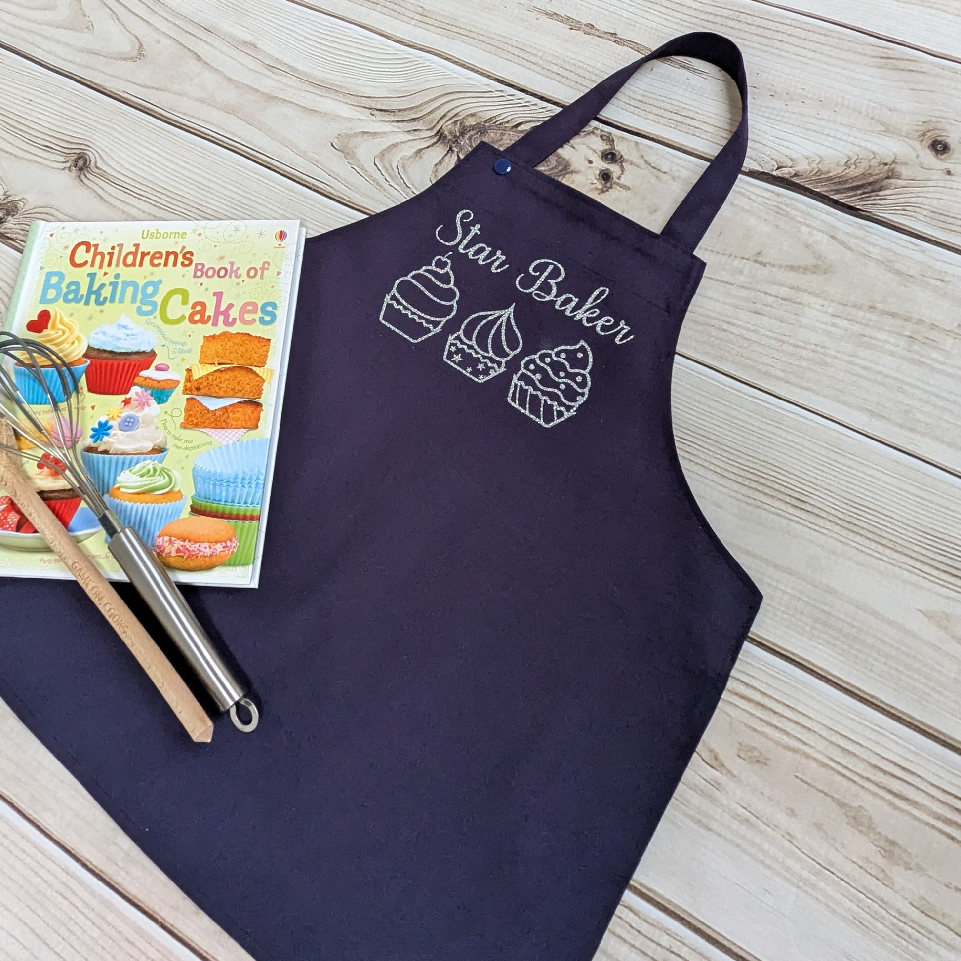 Blue-Handmade-Kids-apron-personalised-text-star-baker-row-of-cupcakes-your-word-choice-book-and-utensils-as-props