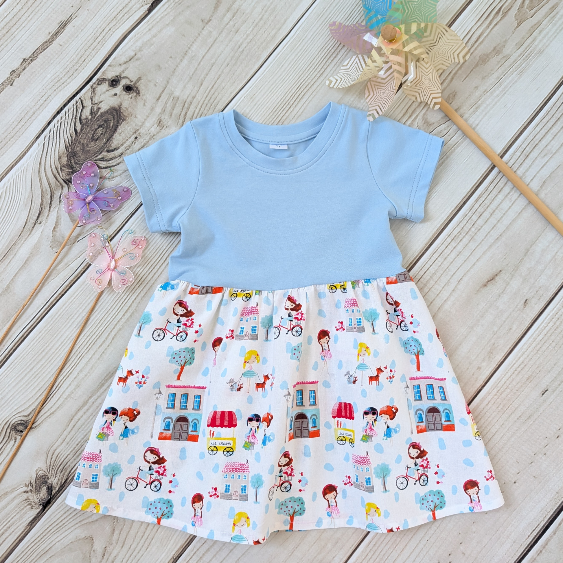 Flatlay-Blue-Bodice-Gathered-Skirt-Girls-Bikes-Ice-Cream-Trees-props-butterflies-and-windmill