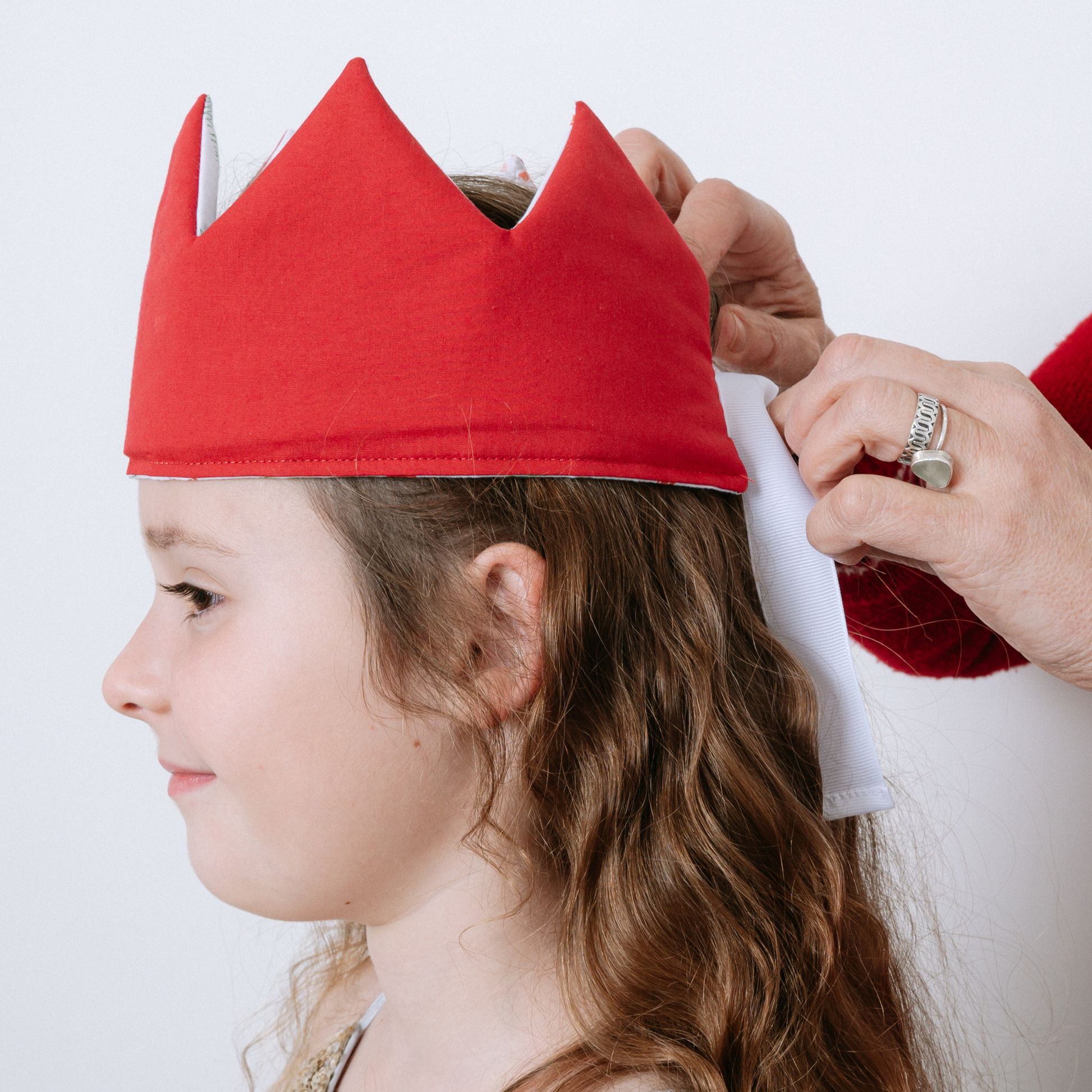 Christmas-reversible-Crown-Red-shown-on-head-with-hands-tying-the-ribbon-red