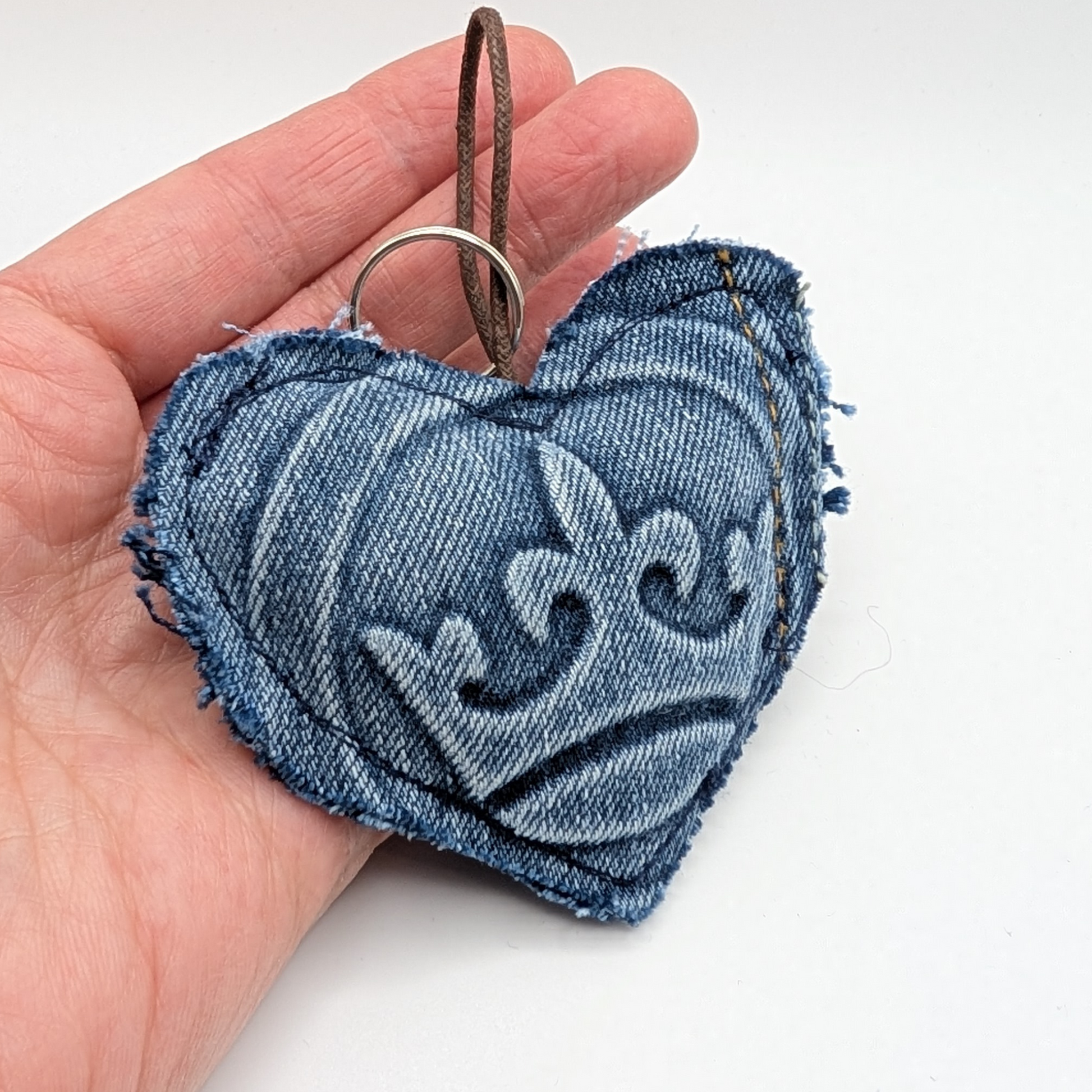 hand-holding-heart-shaped-keyring-with-crown-embossed-detail