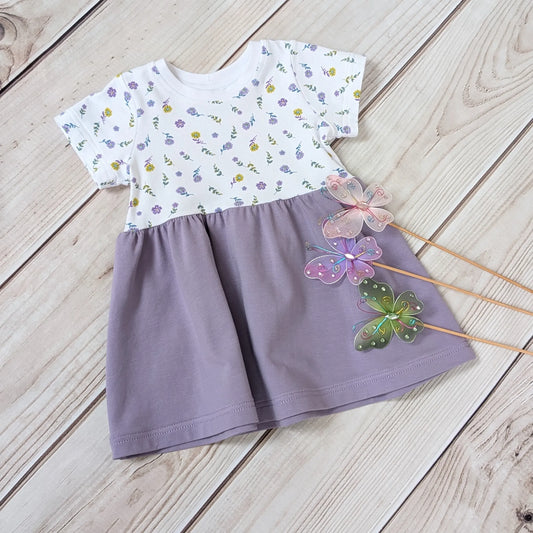 Children's dress with floral top and purple skirt on a wooden surface