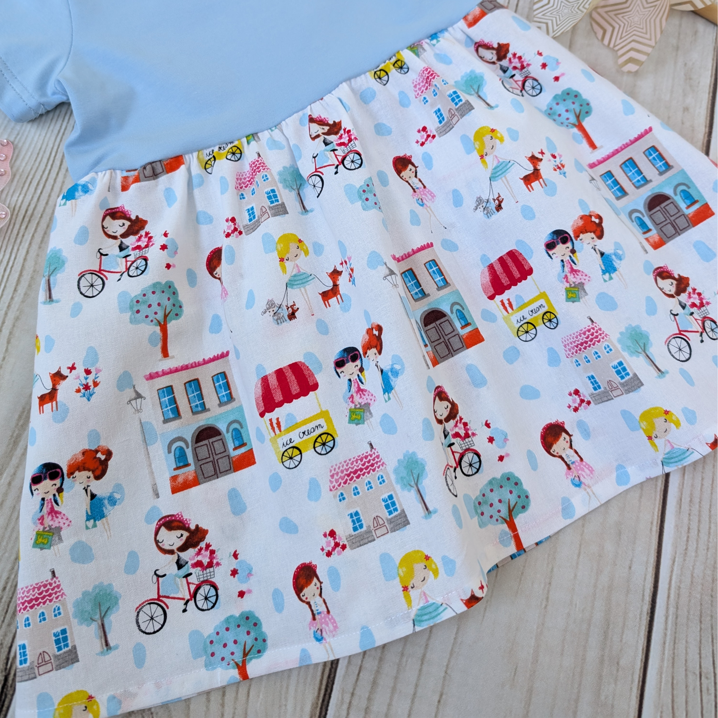 Close-up-Flatlay-Blue-jersey-Bodice-Gathered-cotton-Skirt-Girls-Bikes-Ice-Cream-Trees-props-butterflies-and-windmill