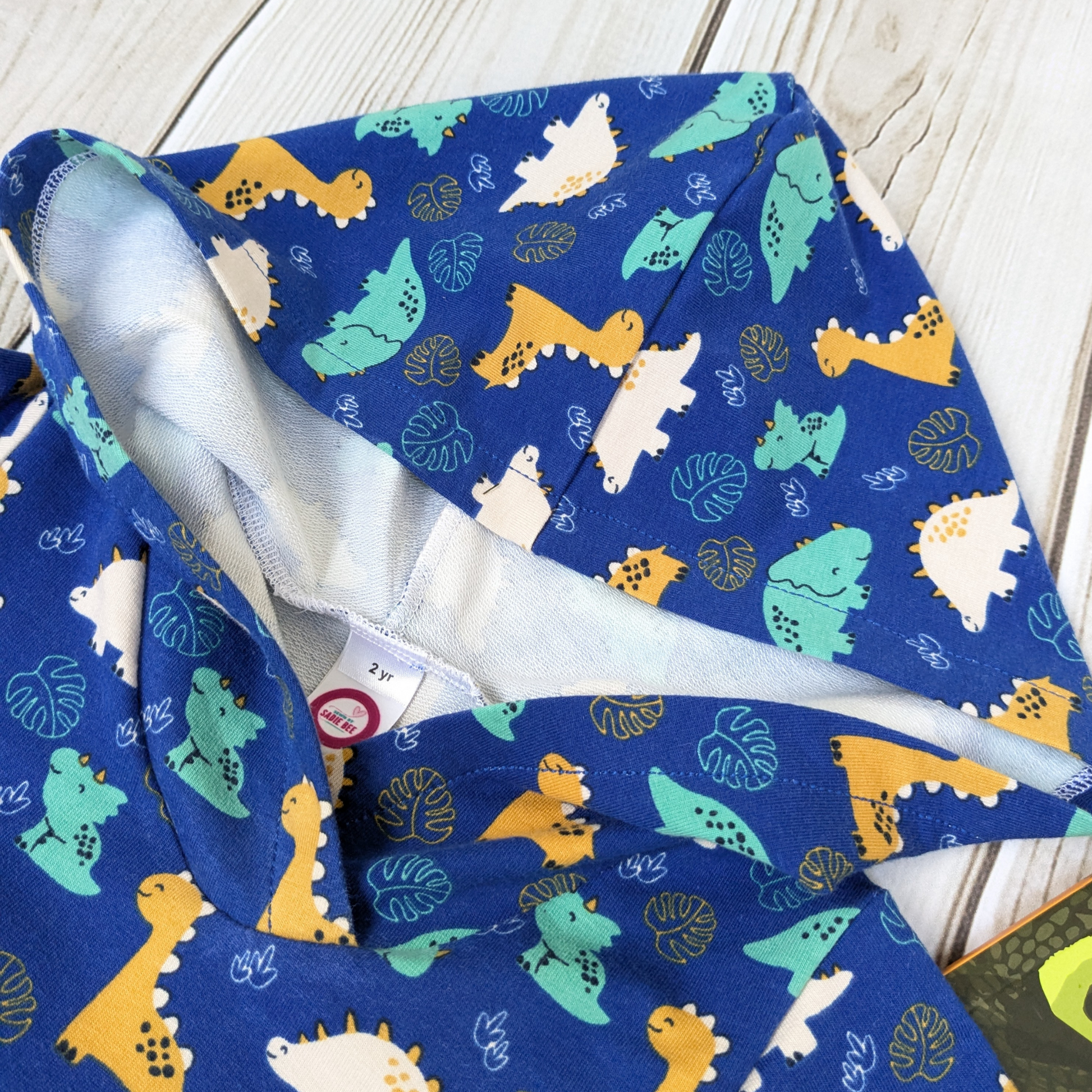 flatlay-dino-pattern-hoodie-blue-smiling-dinosaurs-showing-the-hood