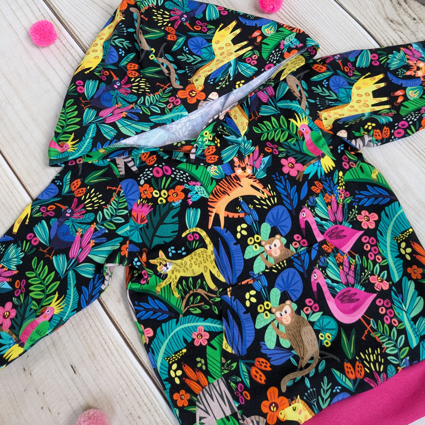 Flatlay-close-up-front-hoodie-pinkcuffs-waistband-animal-design-flamingos-giraffe-tiger-monkeys-cheeta-bird-zebra-foliage-kangeroo-pocket