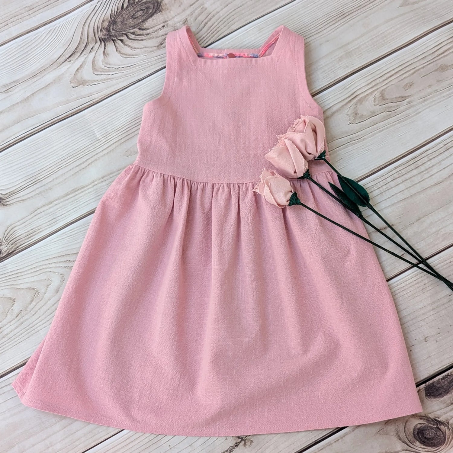 Pink dress on a wooden surface with pink flowers.