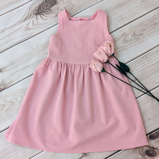 Pink dress on a wooden surface with pink flowers.