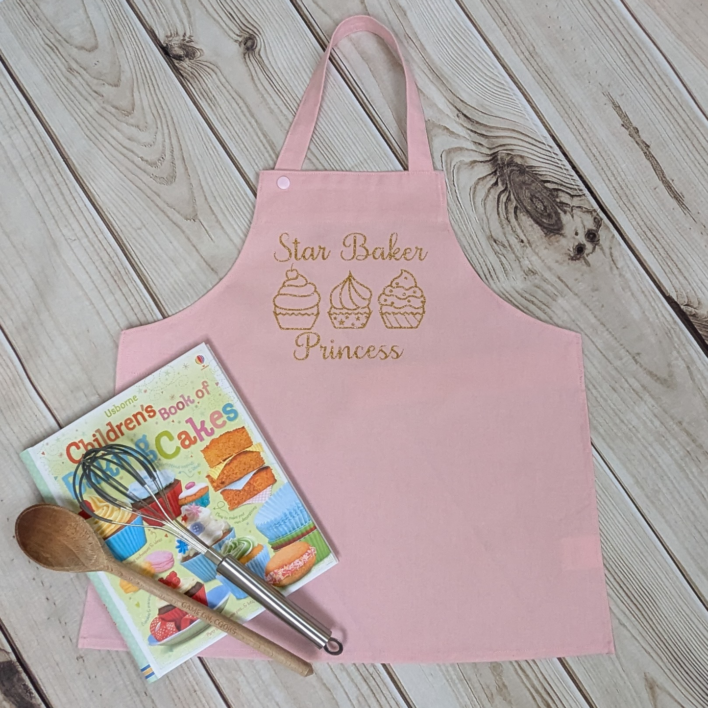 Pink-Handmade-Kids-apron-star-baker-row-of-cupcakes-gold-sparkly-words-book-utensils-props