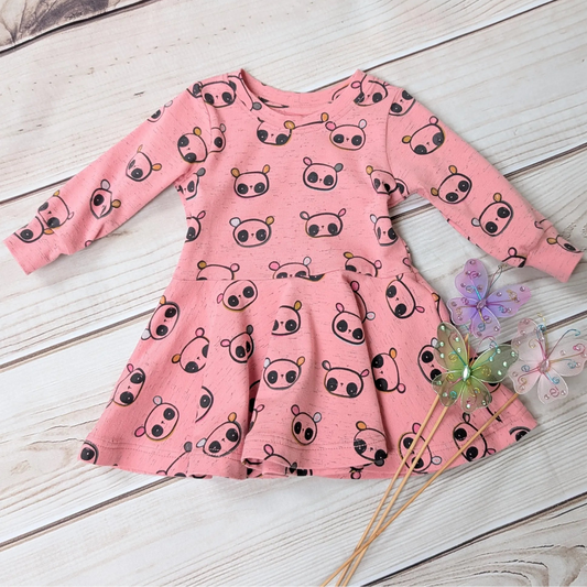 Pink dress with cartoon panda pattern on a wooden surface & butterfly wand props