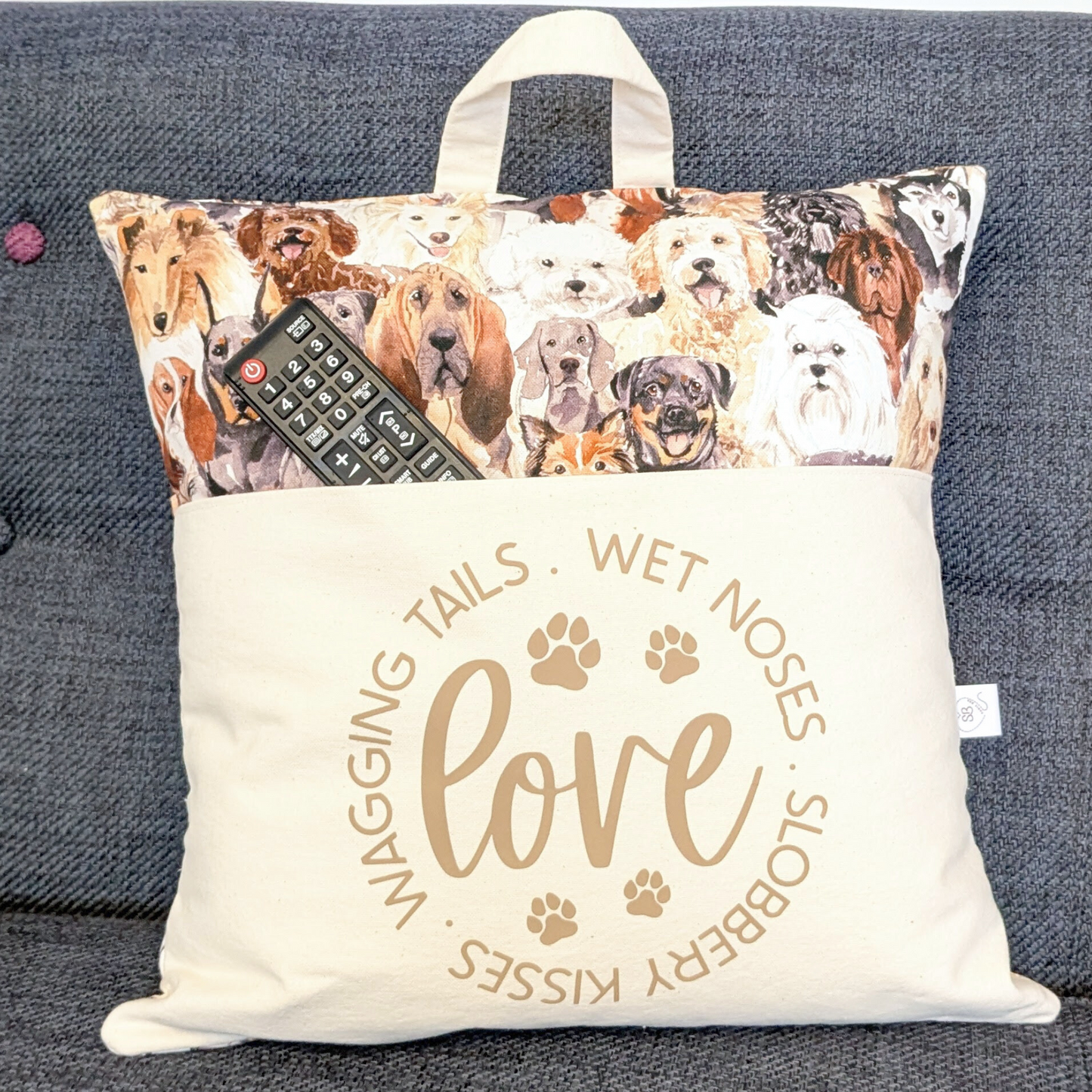 Dog Lover Cushion with pocket. Slogan readsWet Noses, Slobbery Kisses, Wagging Tails. WithRemote Control as a prop,