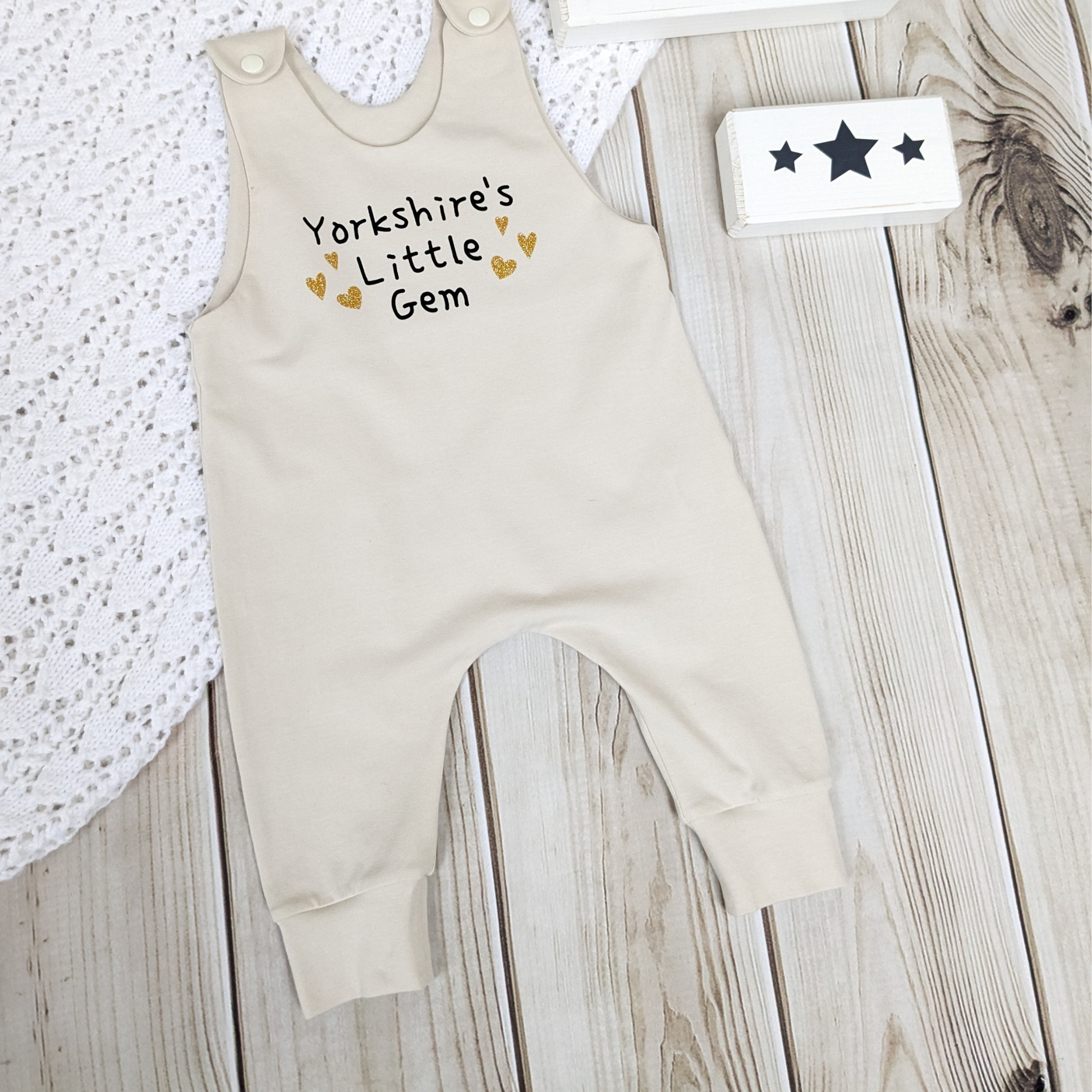 neutral-beige-long-leg-romper-with-phrase-yorkshire's-little-gem-gold-hearts-front-photo-props